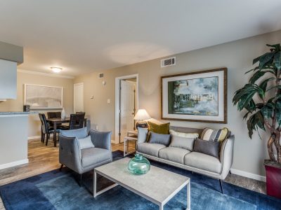 Sunlit staged living room with modern furnishings and wood-style flooring at Clear Creek Landing in Houston, TX