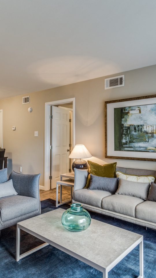 Sunlit staged living room with modern furnishings and wood-style flooring at Clear Creek Landing in Houston, TX