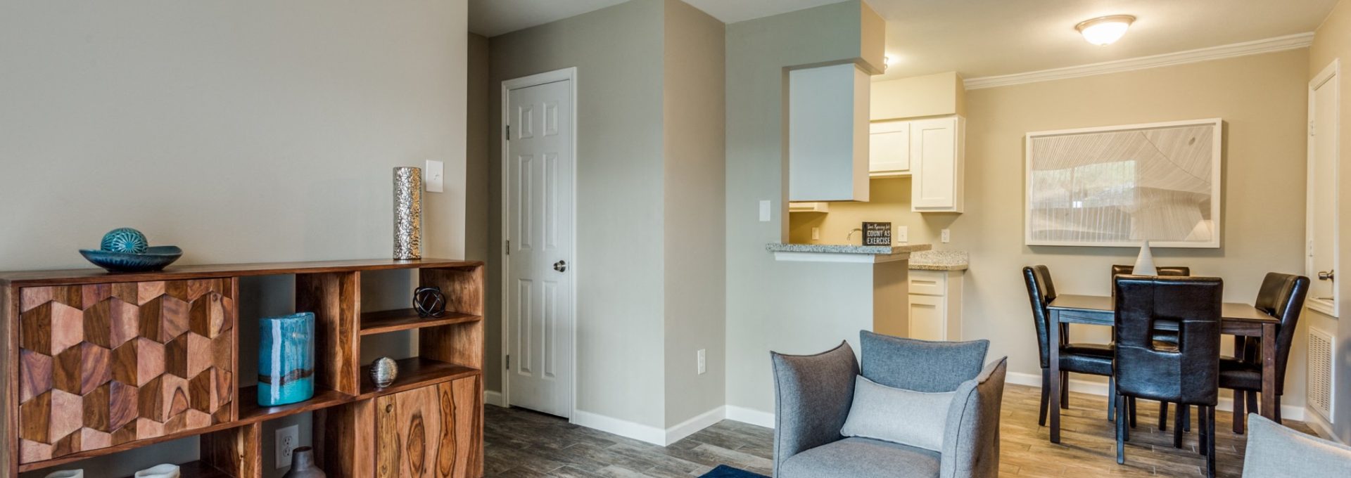 Open living and dining area with media console and wood-style flooring at Clear Creek Landing in Houston, TX