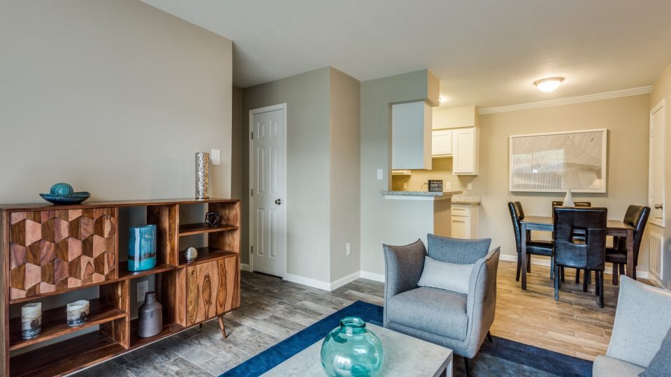 Open living and dining area with media console and wood-style flooring at Clear Creek Landing in Houston, TX