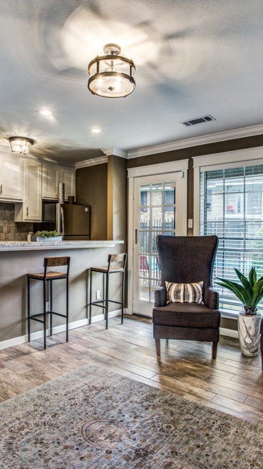 Renovated open-concept living room and kitchen with wood-style flooring at Clear Creek Landing in Houston, TX