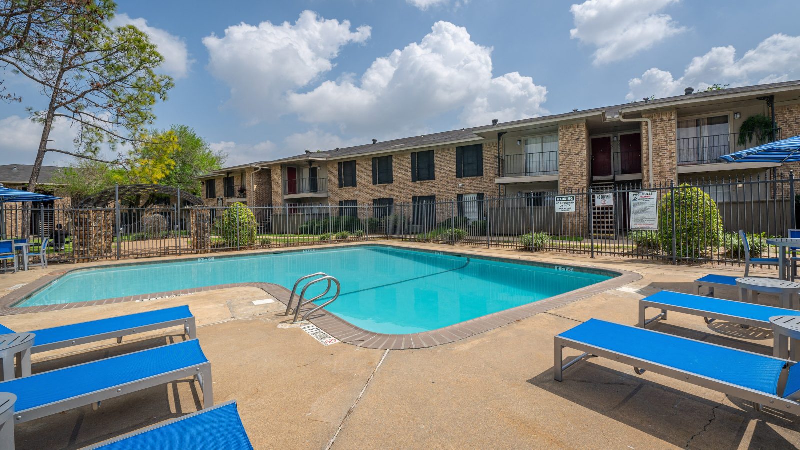 Sparkling swimming pool with sun deck and brick apartment buildings at Clear Creek Landing in Houston, TX