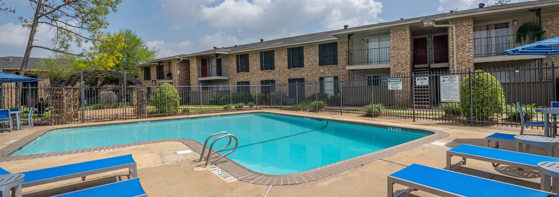 Sparkling swimming pool with sun deck and brick apartment buildings at Clear Creek Landing in Houston, TX
