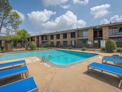 Sparkling swimming pool with sun deck and brick apartment buildings at Clear Creek Landing in Houston, TX