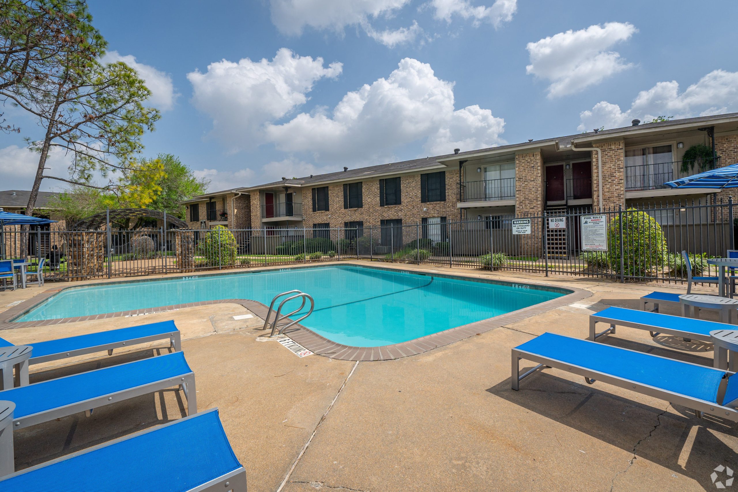 Sparkling swimming pool with sun deck and brick apartment buildings at Clear Creek Landing in Houston, TX