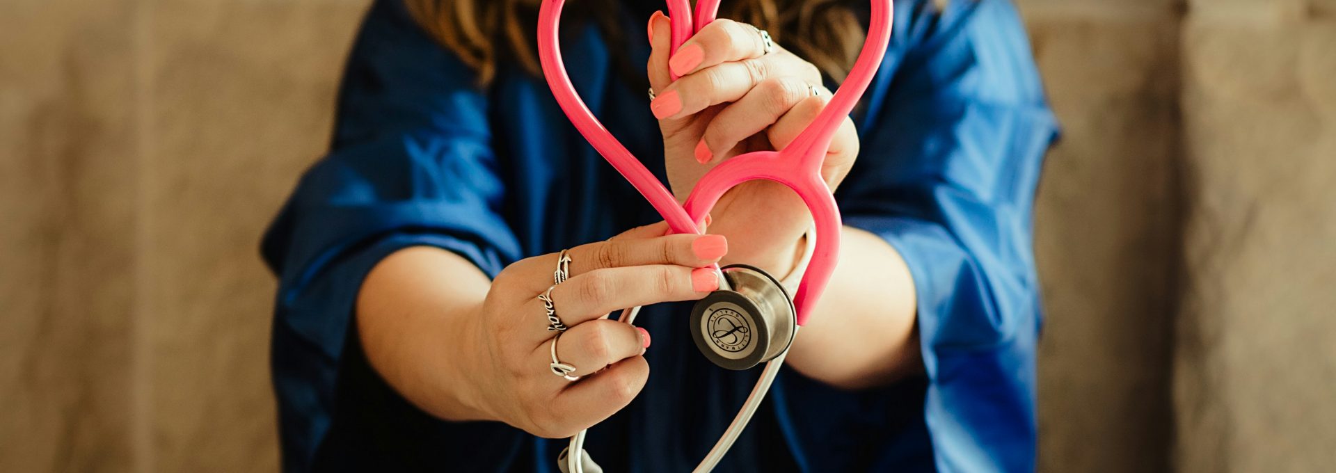 woman in scrubs holding heart shaped stethoscope