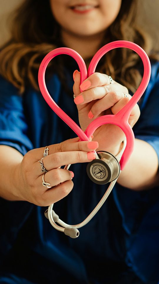 woman in scrubs holding heart shaped stethoscope
