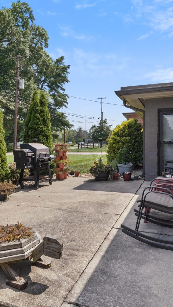 Outdoor patio with rocking chairs, planters and a grill at The Park at Fountain City Apartments in Knoxville, Tennessee