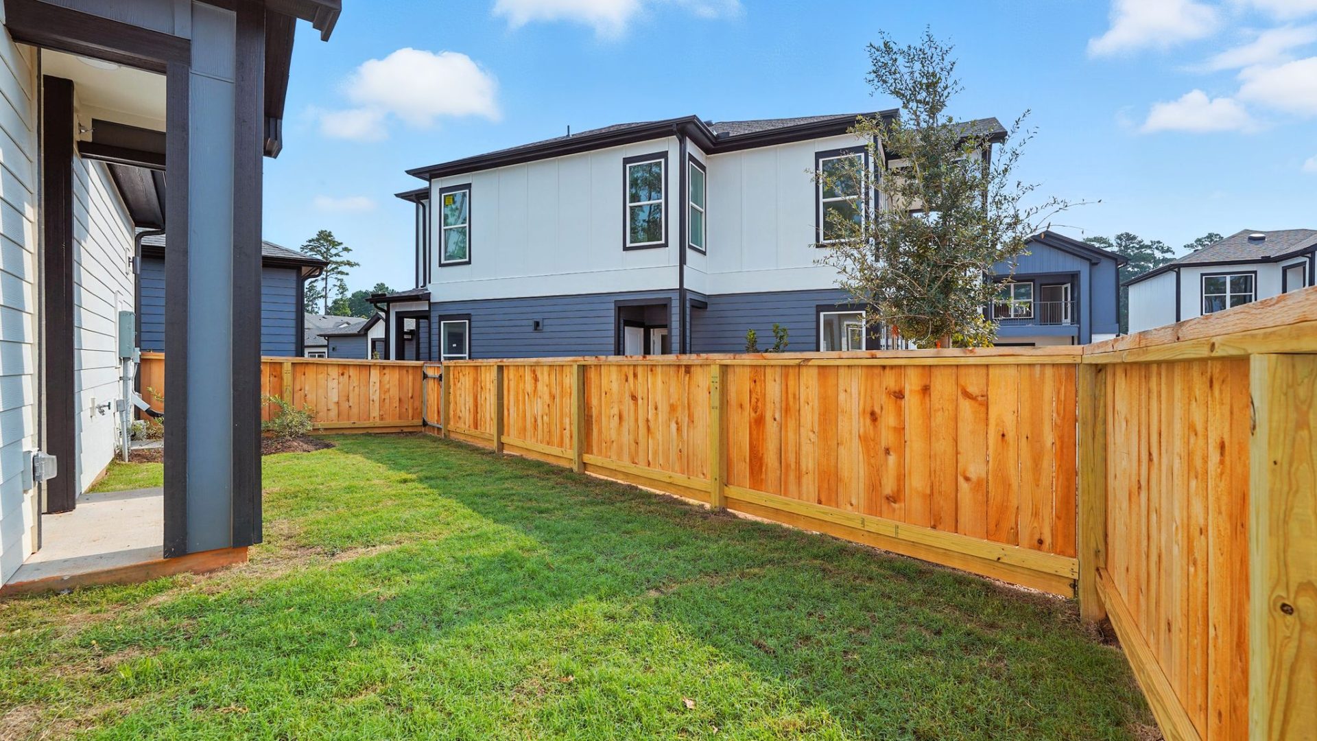 3-Bedroom Homes for Rent in Conroe, TX - Soltera Rolling Pines - Yard With Wood Privacy Fence, Green Lawn, And Neighborhood Home Views Under Bright Blue Sky.