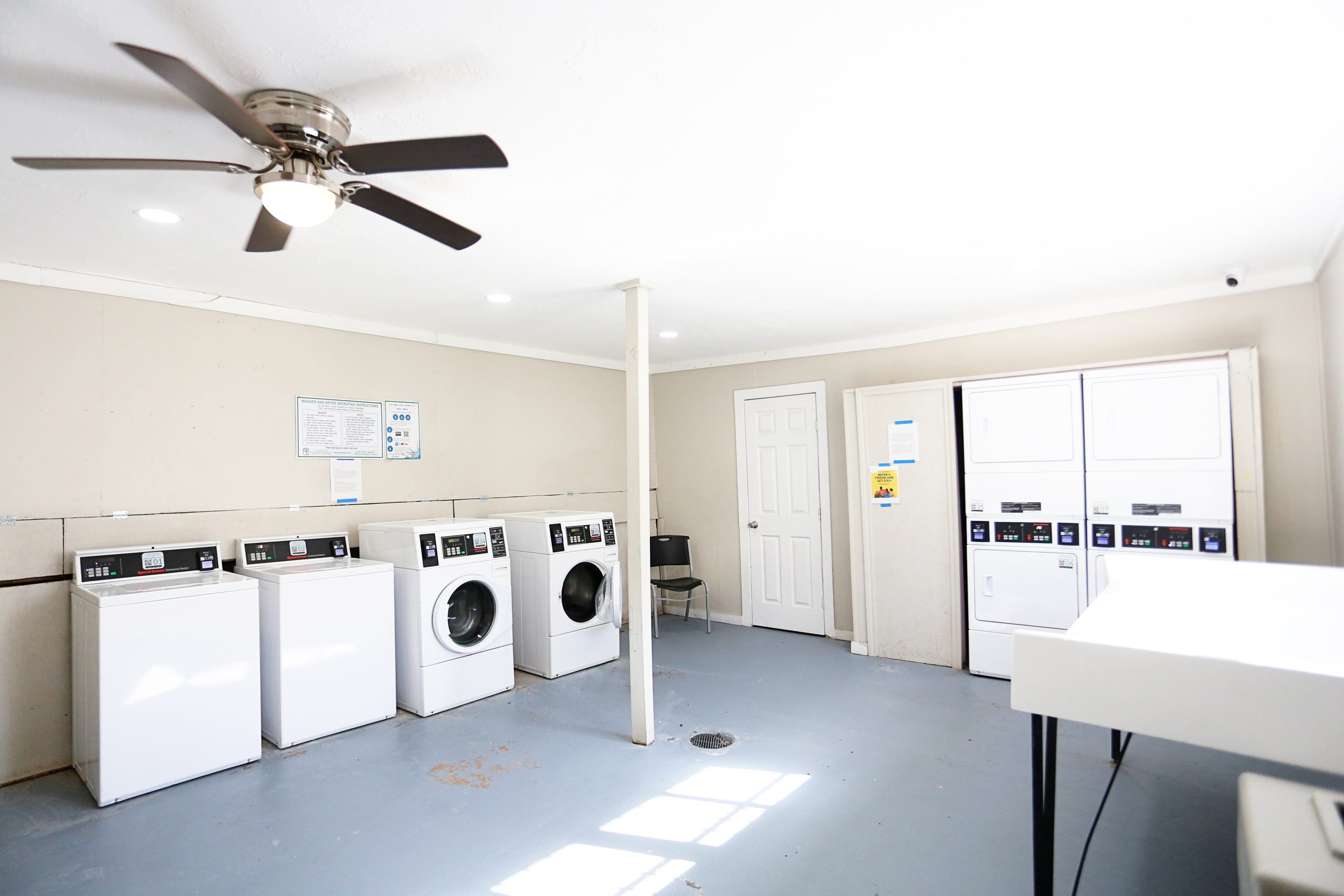 a laundry room with washers and dryers and a ceiling fan at The Vista Villa Apartments