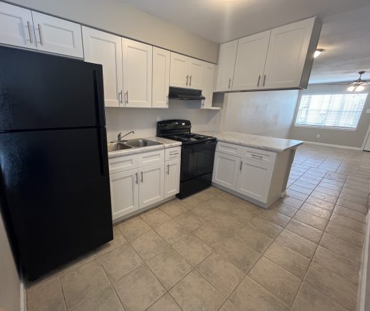 a kitchen with black appliances and white cabinets at The Vista Villa Apartments