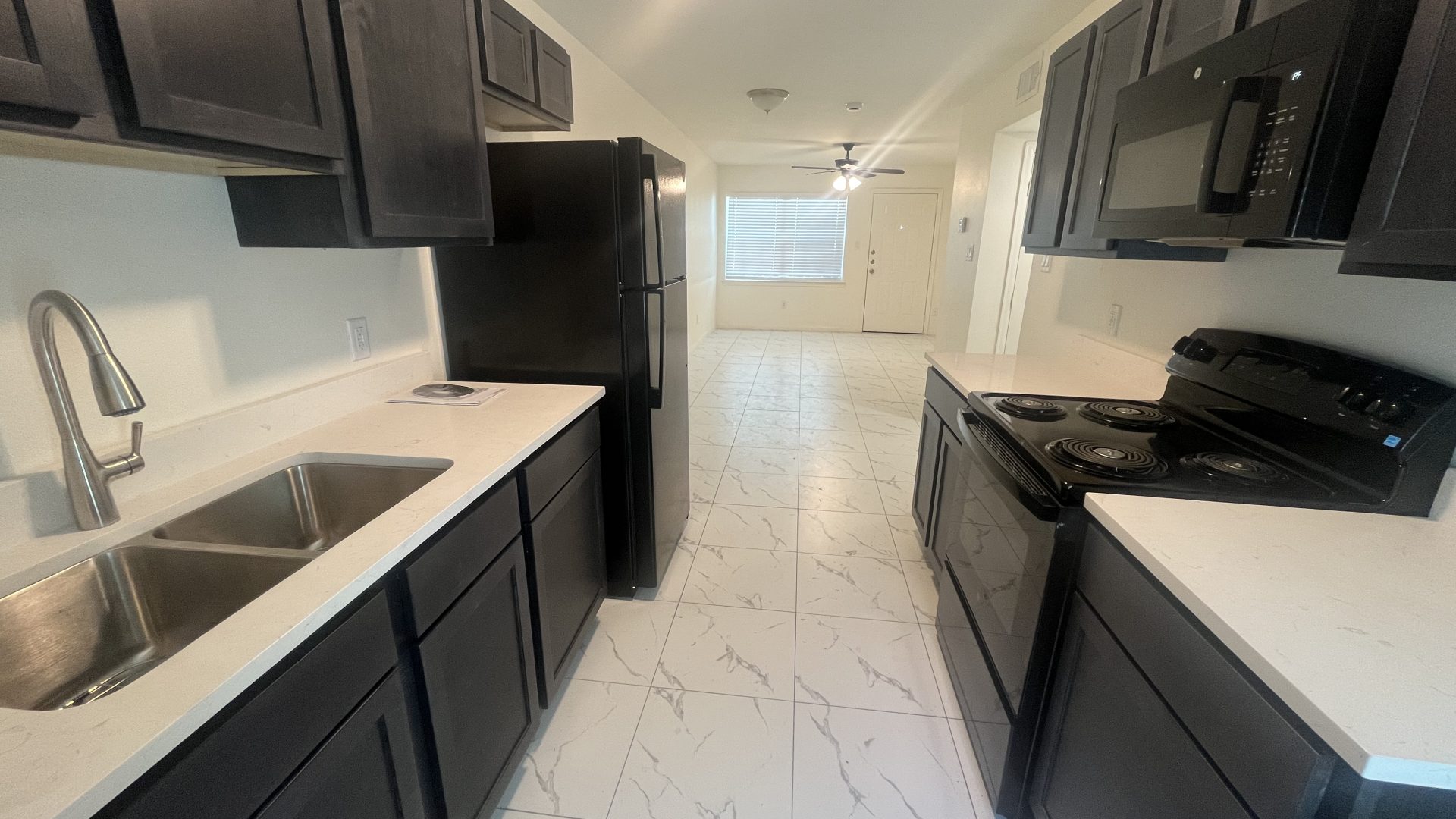 a kitchen with a sink, stove, microwave and refrigerator