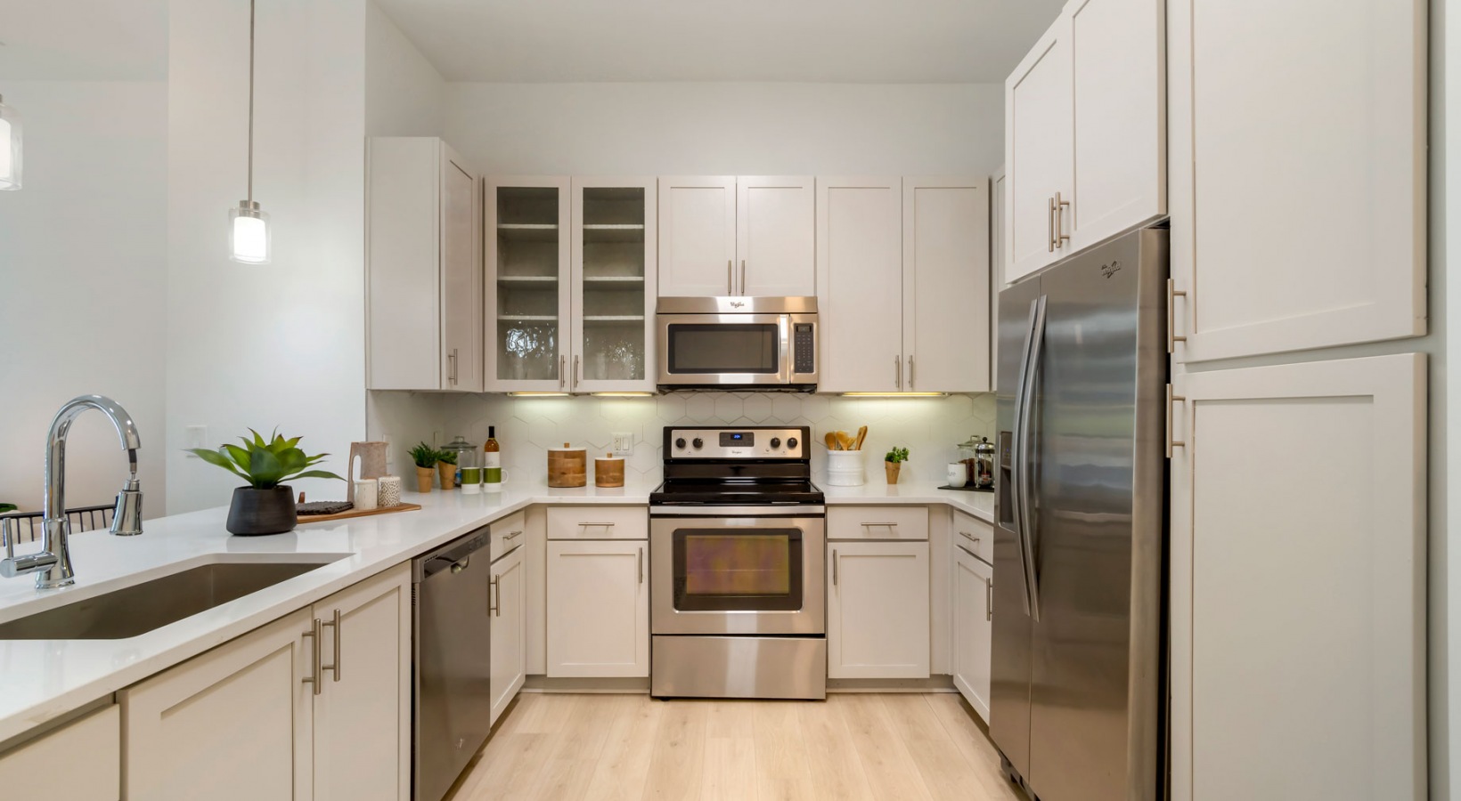a kitchen with stainless steel appliances and white cabinets at The Allure