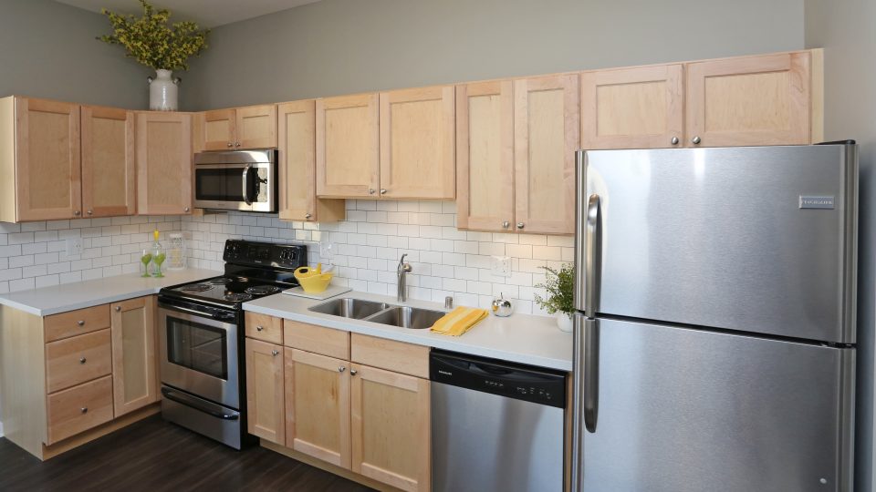 a kitchen with stainless steel appliances and wood cabinets at The Germania Apartments