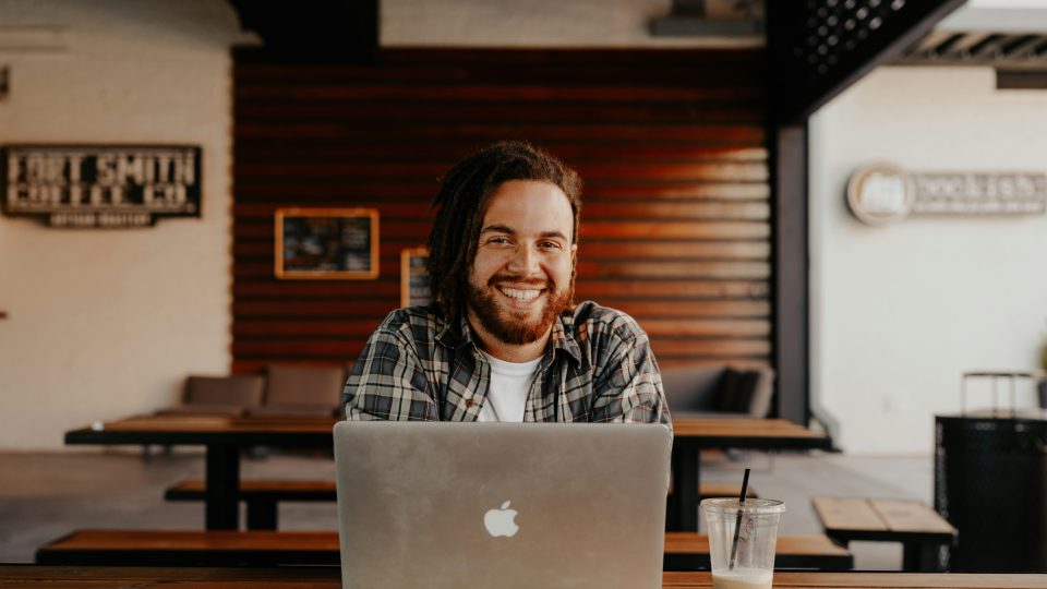 man in black and white striped polo shirt sitting on chair in front of silver macbook