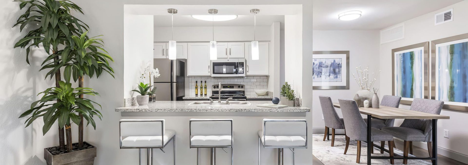a clean and modern kitchen with white cabinets and hardwood floors at The  Adelene