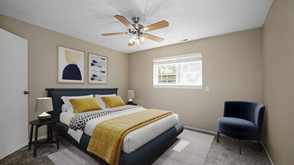 a bedroom with a bed, a ceiling fan and a large window at The Windchase Flats and Townhomes