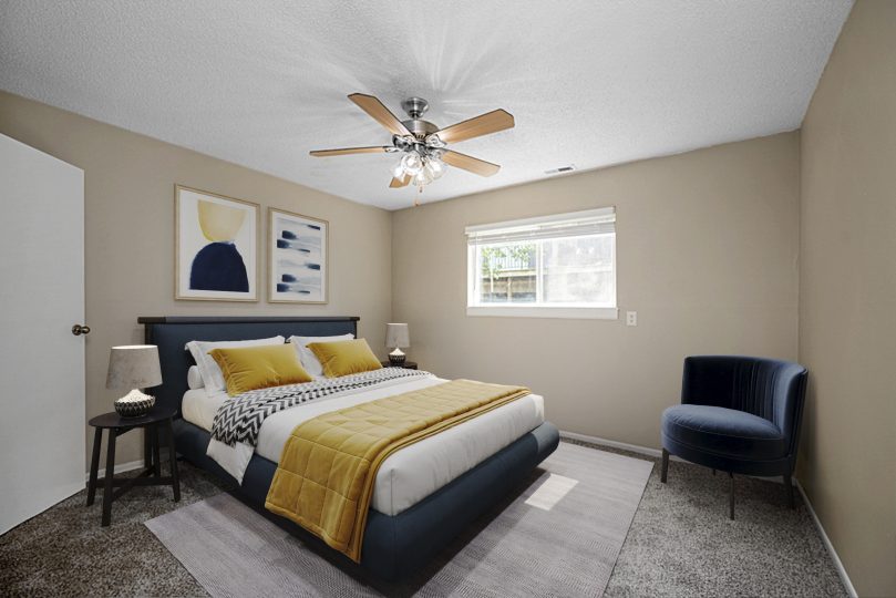 a bedroom with a bed, a ceiling fan and a large window at The Windchase Flats and Townhomes