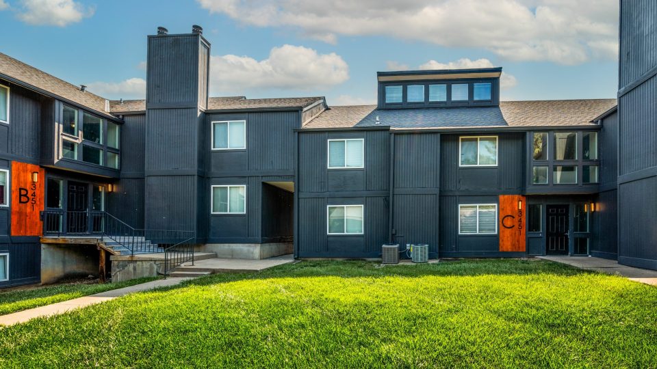 the exterior of an apartment complex with orange and black trim at The Windchase Flats and Townhomes