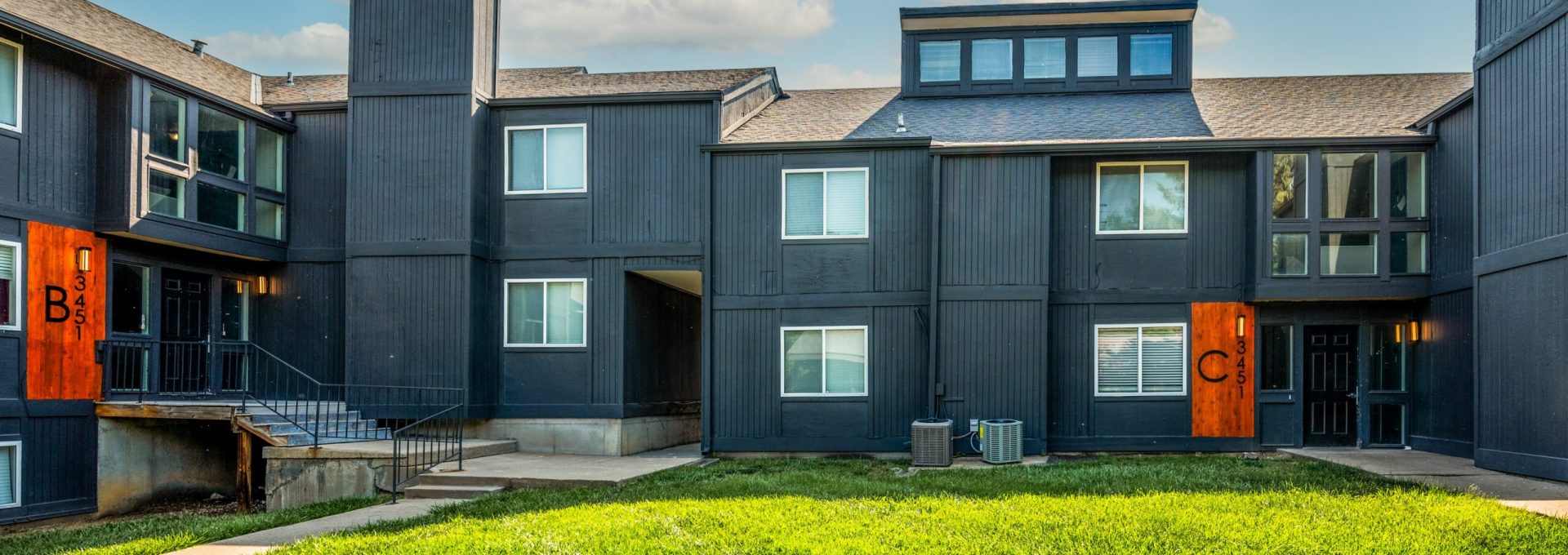 the exterior of an apartment complex with orange and black trim at The Windchase Flats and Townhomes