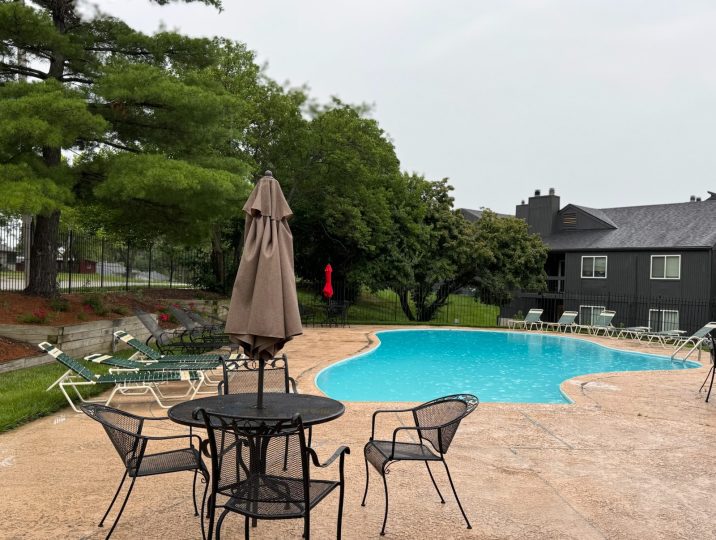 a pool with chairs and umbrellas near a patio at The Windchase Flats and Townhomes
