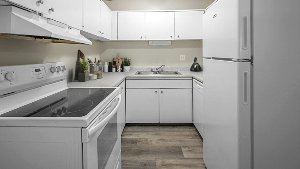 a white kitchen with white appliances and a stove at The Windchase Flats and Townhomes
