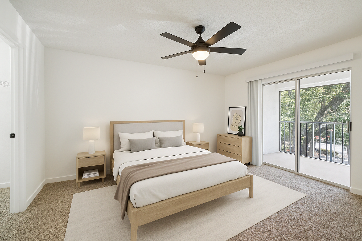 A serene and modern bedroom features a neatly made bed with white linens and a wooden headboard, flanked by nightstands with lamps. A ceiling fan with a light fixture hangs above, providing illumination. The room includes a wooden dresser with decorative items and a large window that opens to a balcony with a view of lush greenery. The space exudes a calm and inviting atmosphere, perfect for relaxation and rest.