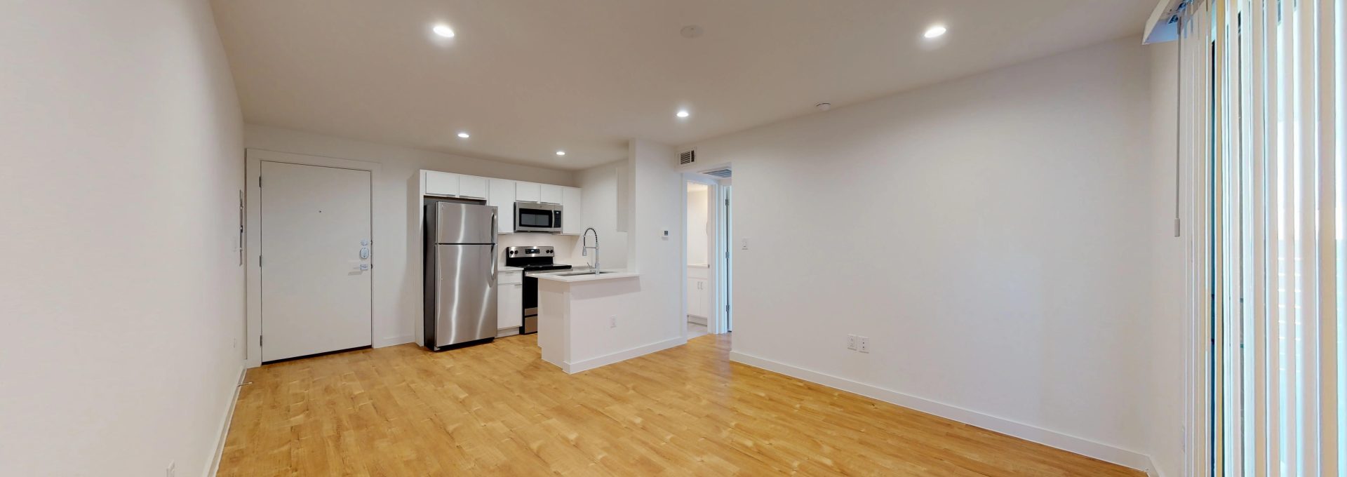 an empty room with hardwood floors and a refrigerator at The Flamingo