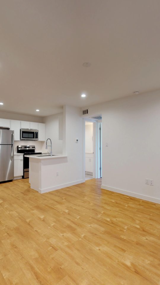 an empty room with hardwood floors and a refrigerator at The Flamingo