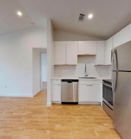 a kitchen with stainless steel appliances and hardwood floors at The Flamingo