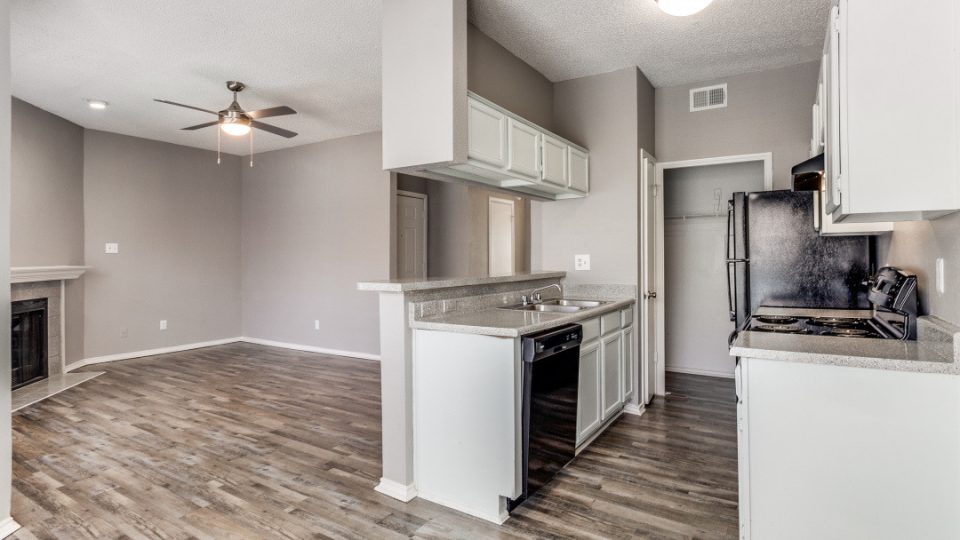 an empty kitchen with hardwood floors and a ceiling fan at The Huntington Brook