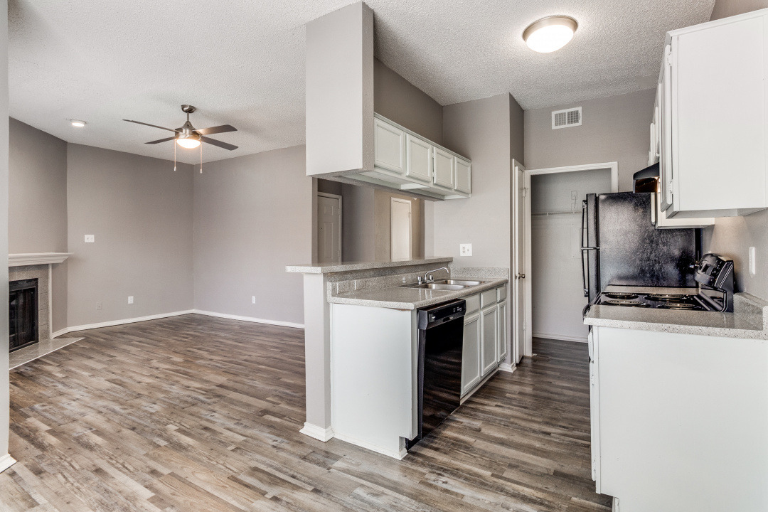 an empty kitchen with hardwood floors and a ceiling fan at The Huntington Brook