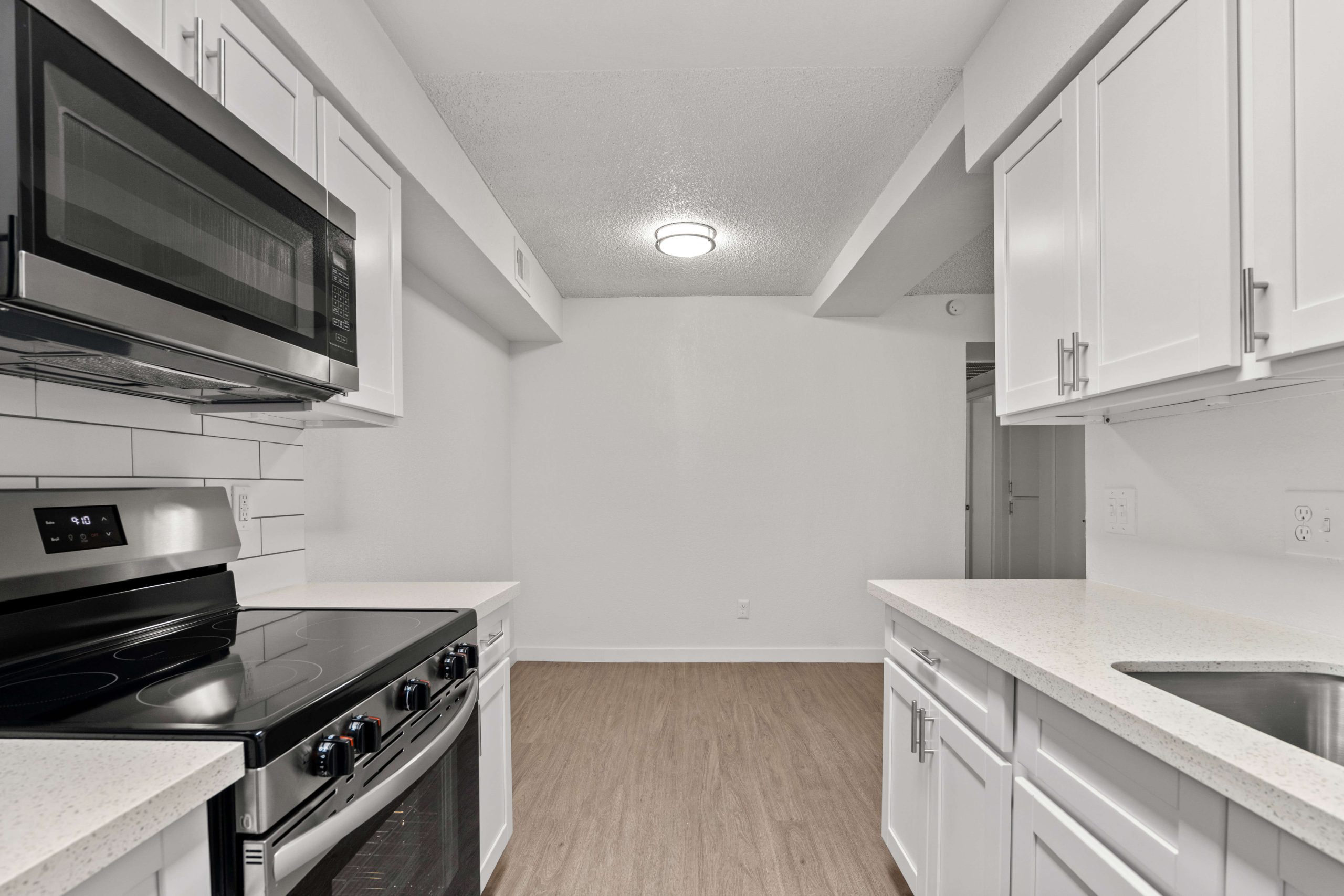 a kitchen with white cabinets and stainless steel appliances at The Tides on 27th