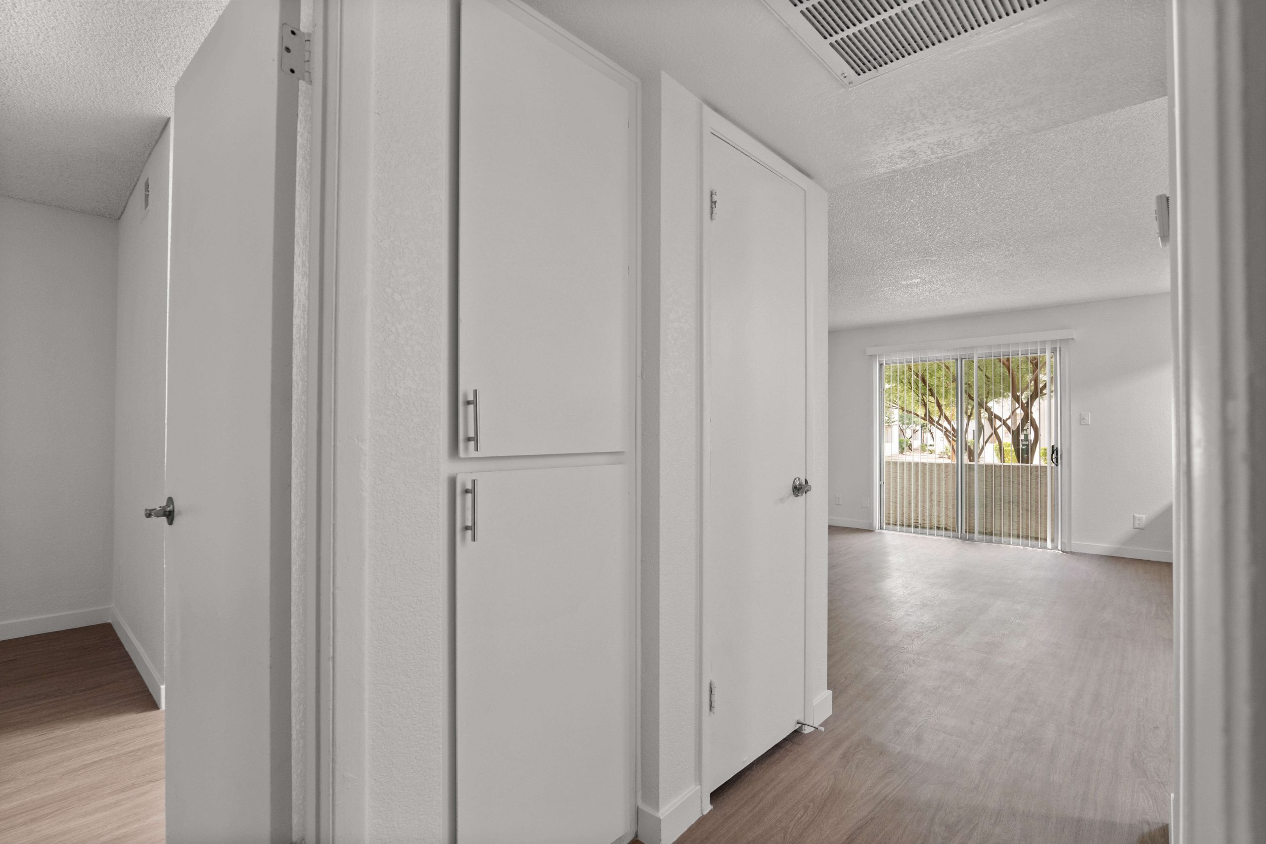an empty room with white walls and hardwood floors at The Tides on 27th