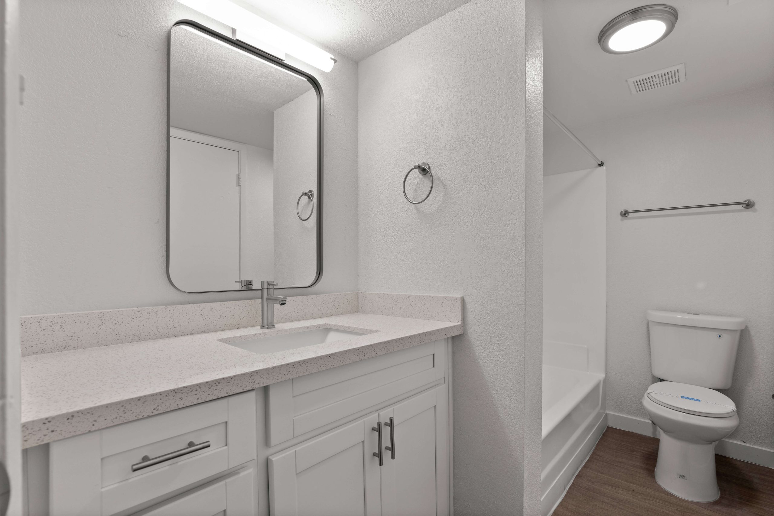 a bathroom with a toilet, sink and mirror at The Tides on 27th