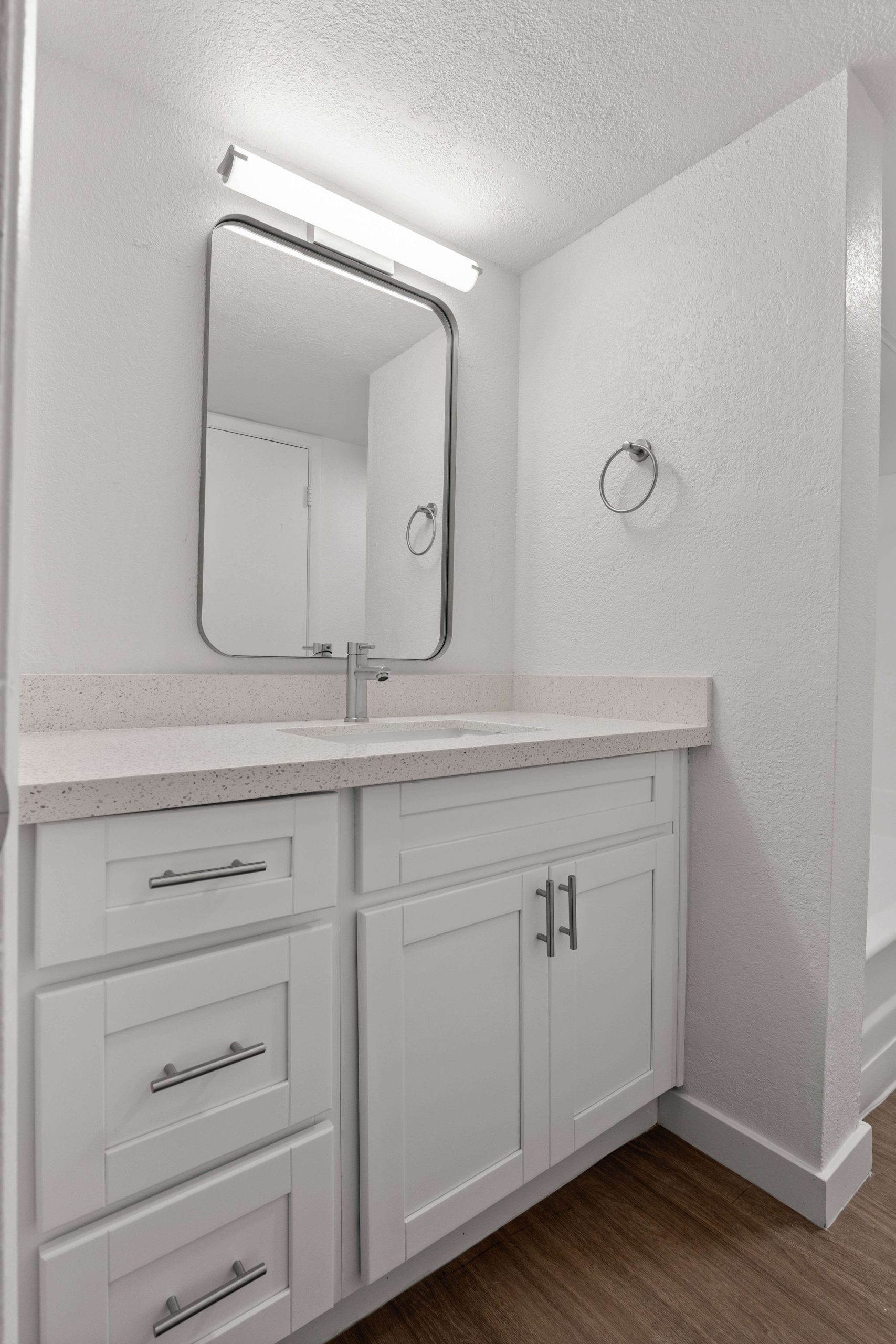 a bathroom with a white vanity and mirror at The Tides on 27th