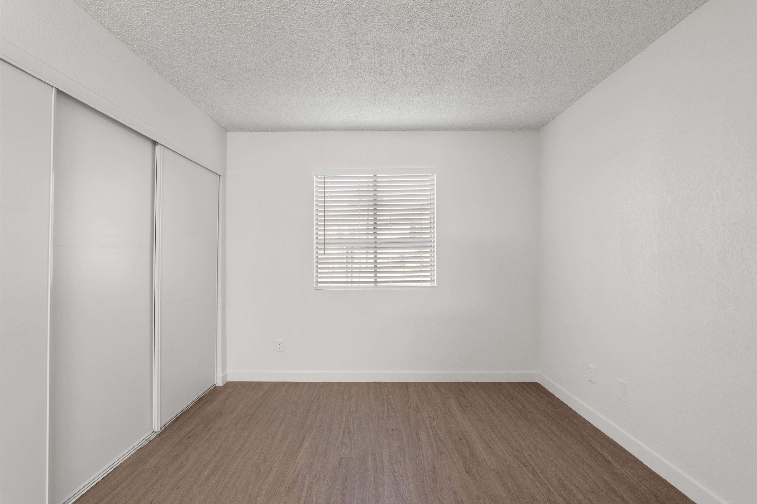 empty room with white walls and hardwood floors at The Tides on 27th