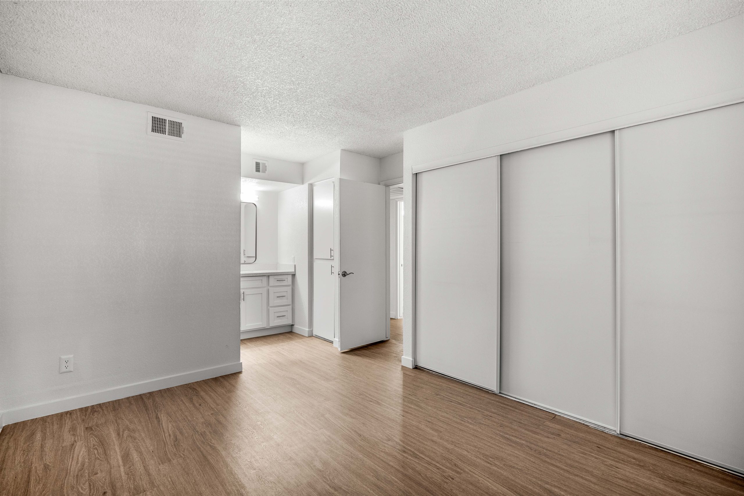 an empty room with white walls and hardwood floors at The Tides on 27th