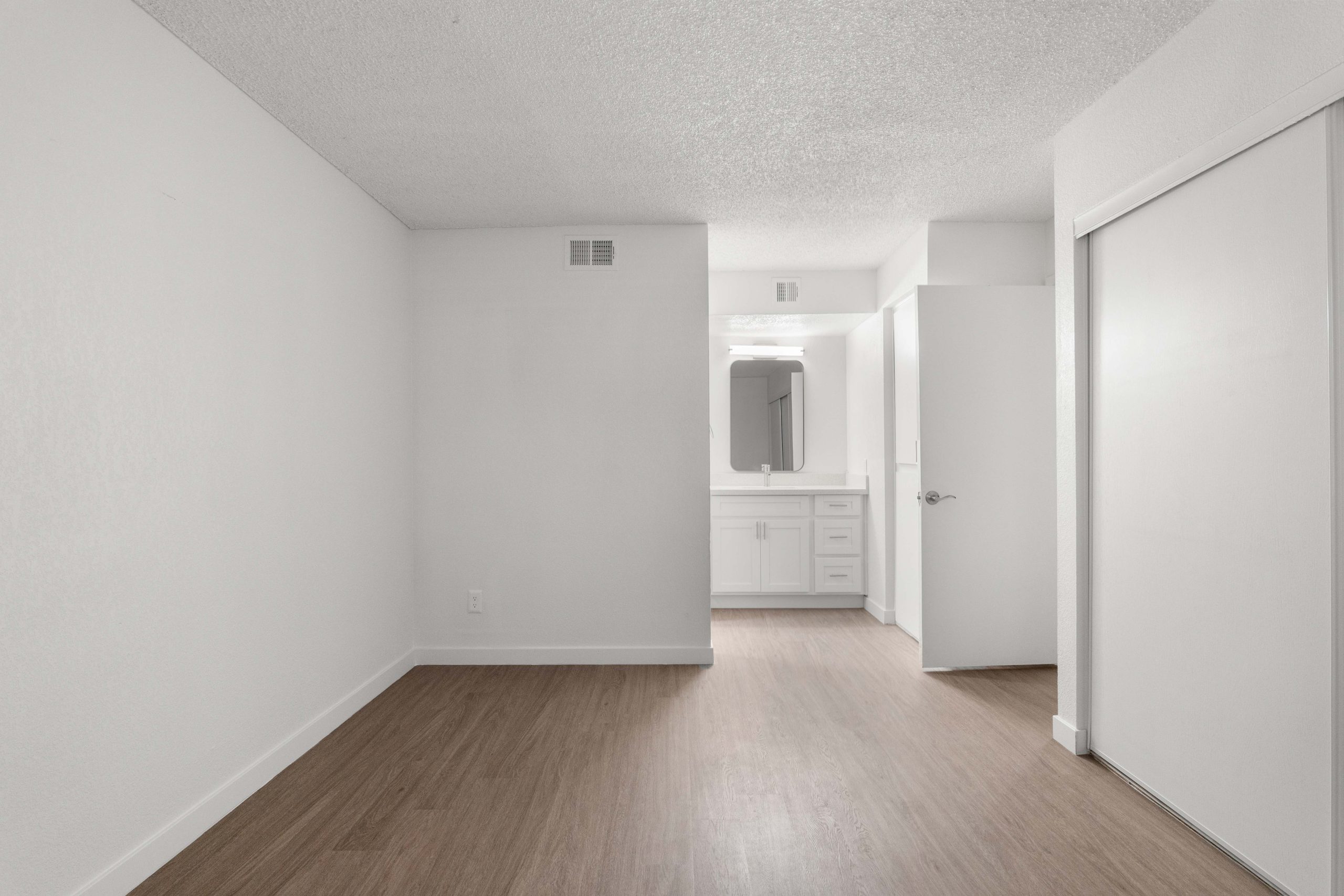 empty room with white walls and hardwood floors at The Tides on 27th