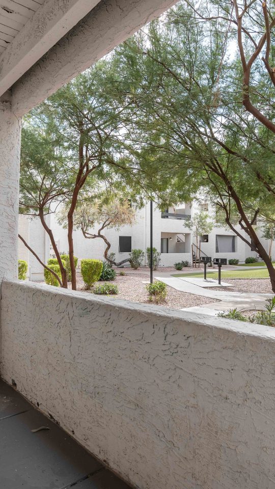 a balcony with a view of trees and a sidewalk at The Tides on 27th