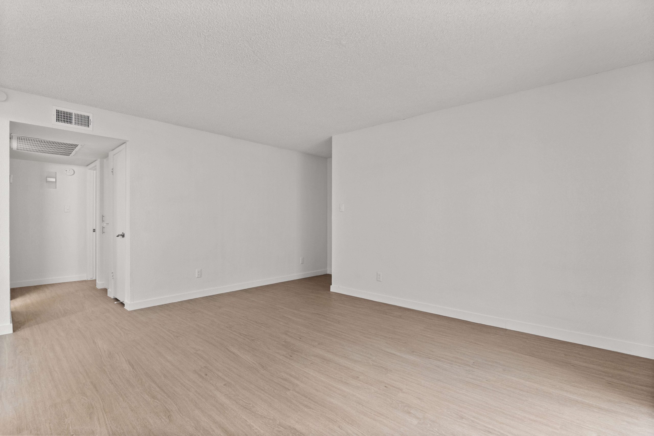an empty room with hardwood floors and white walls at The Tides on 27th