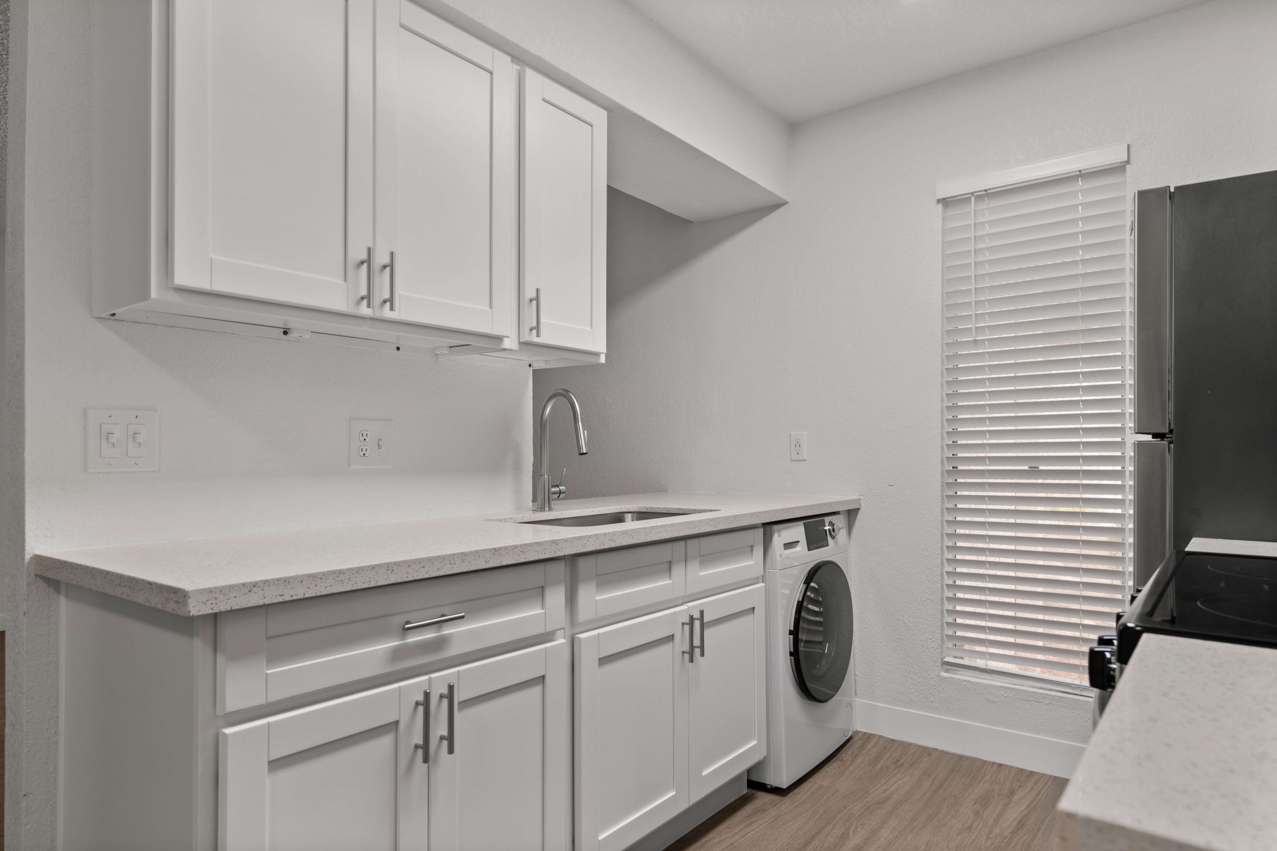 a white kitchen with a washer and dryer at The Tides on 27th