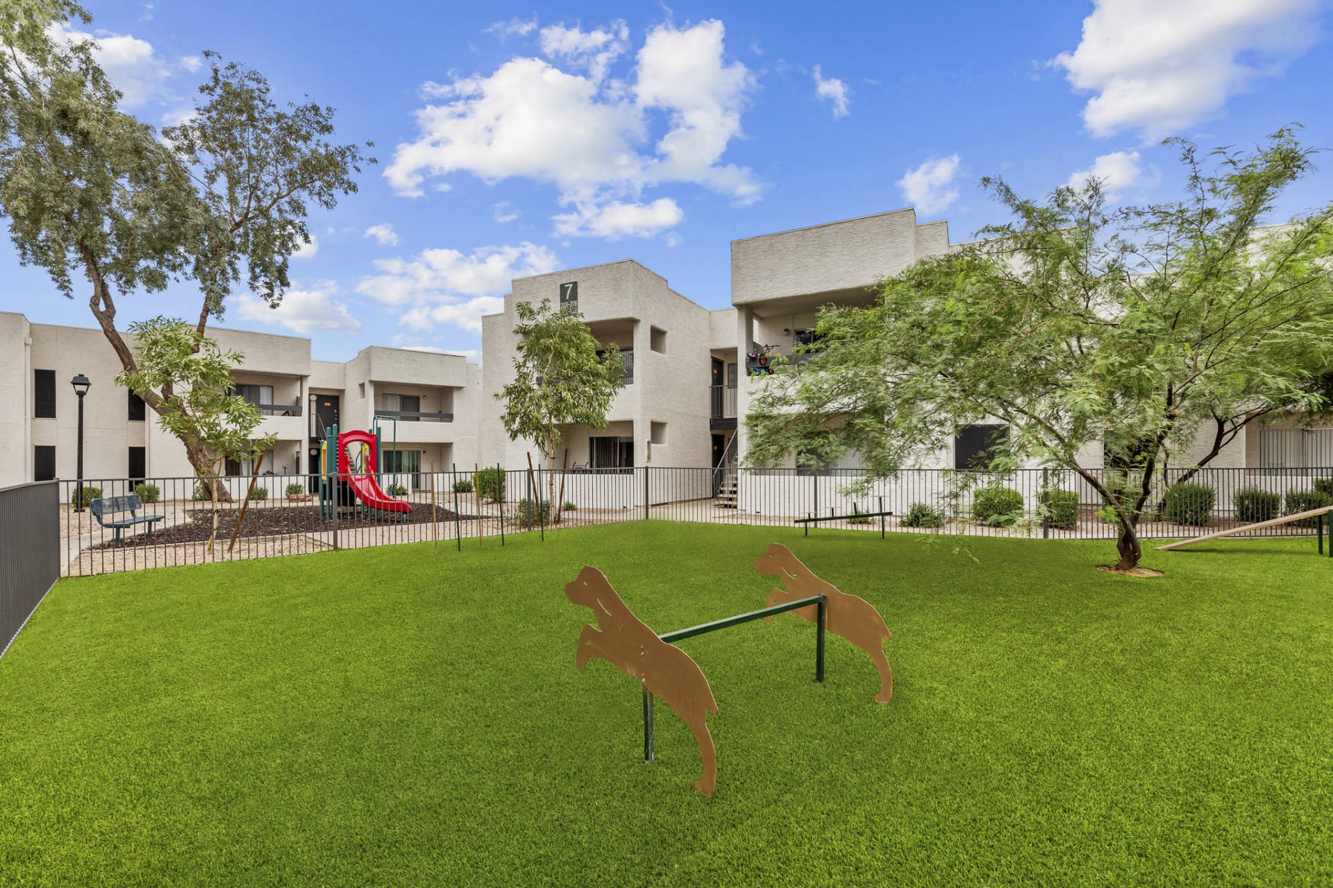 a dog park in front of a large apartment complex at The Tides on 27th