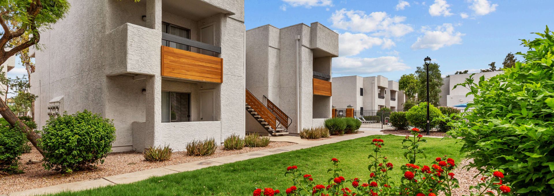 the exterior of an apartment complex with flowers and bushes at The Tides on 27th