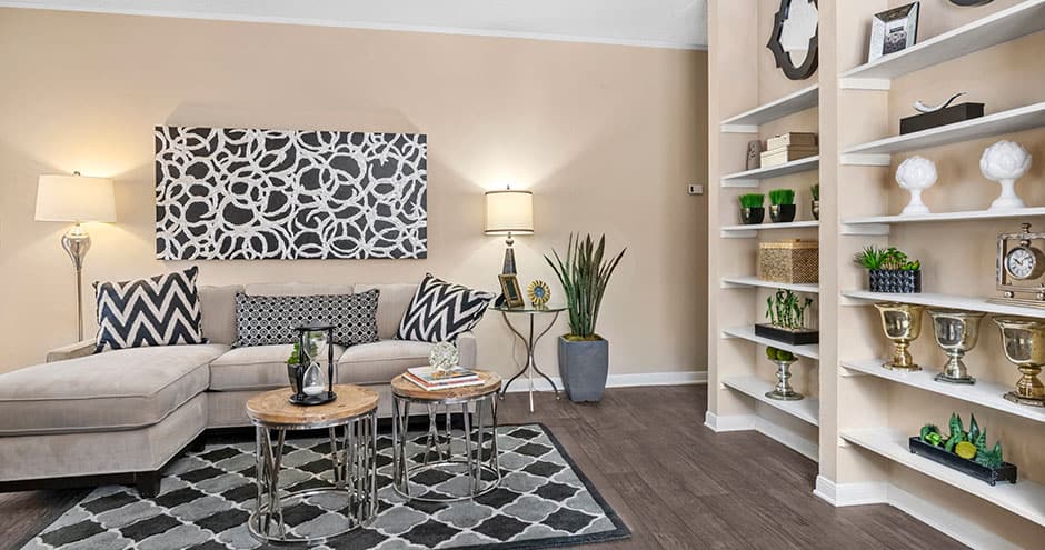 a living room with a white couch and black and white flooring at The  Woodlands Apartments