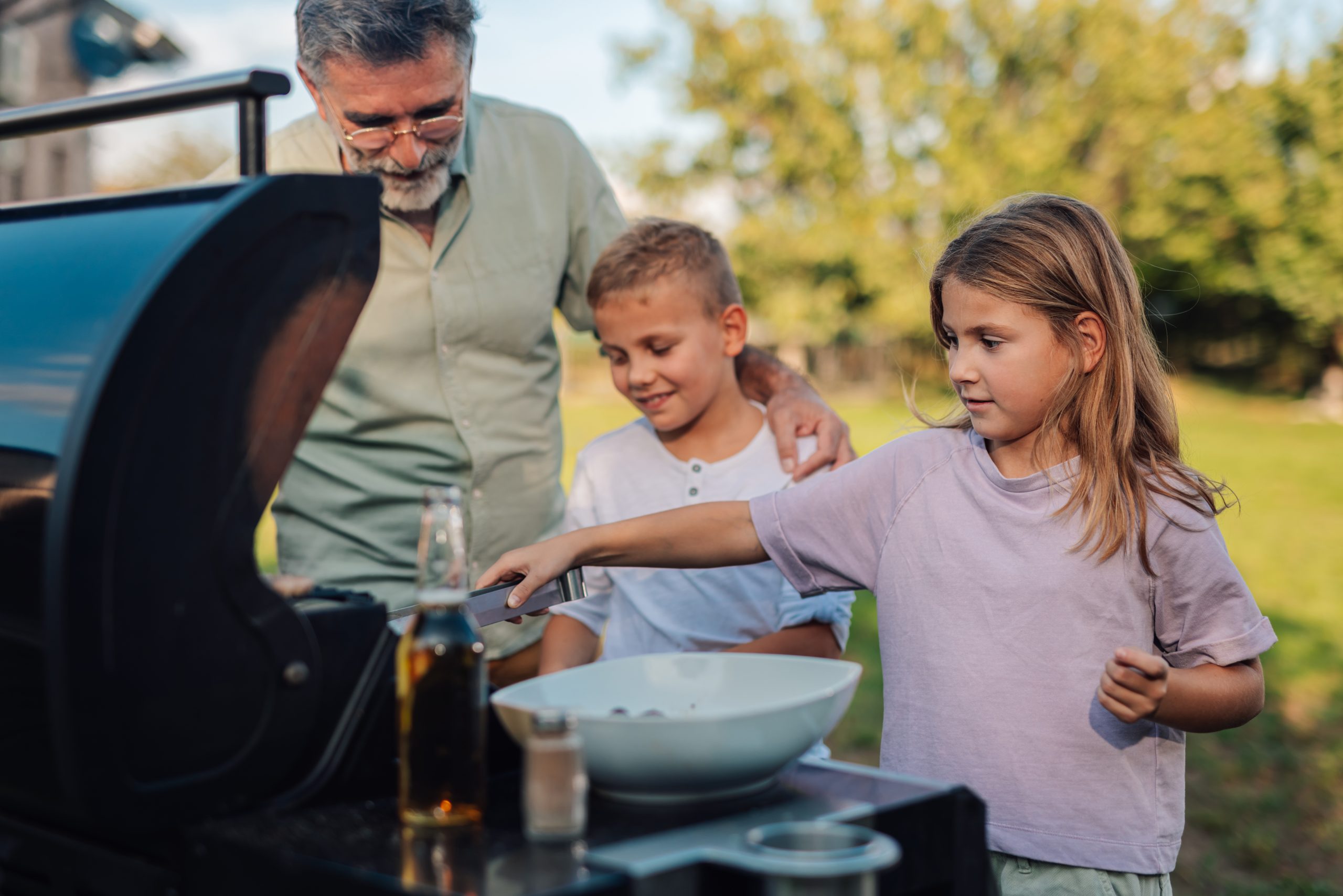 a man and two children are cooking on a grill at The Woodview