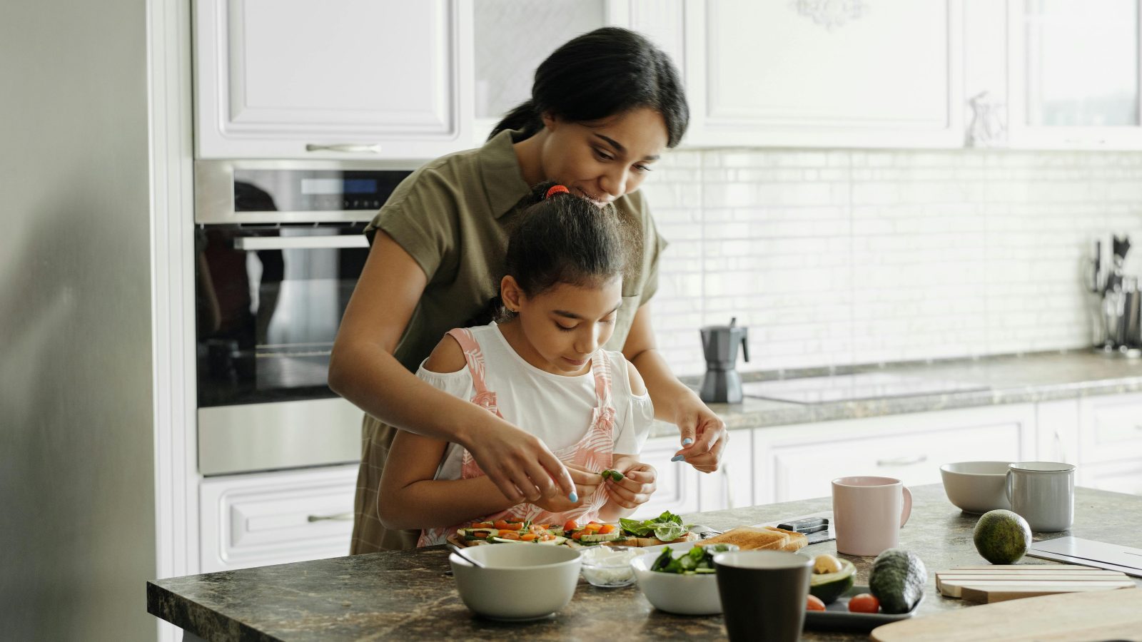 a woman and child are preparing food in the kitchen at The Woodview