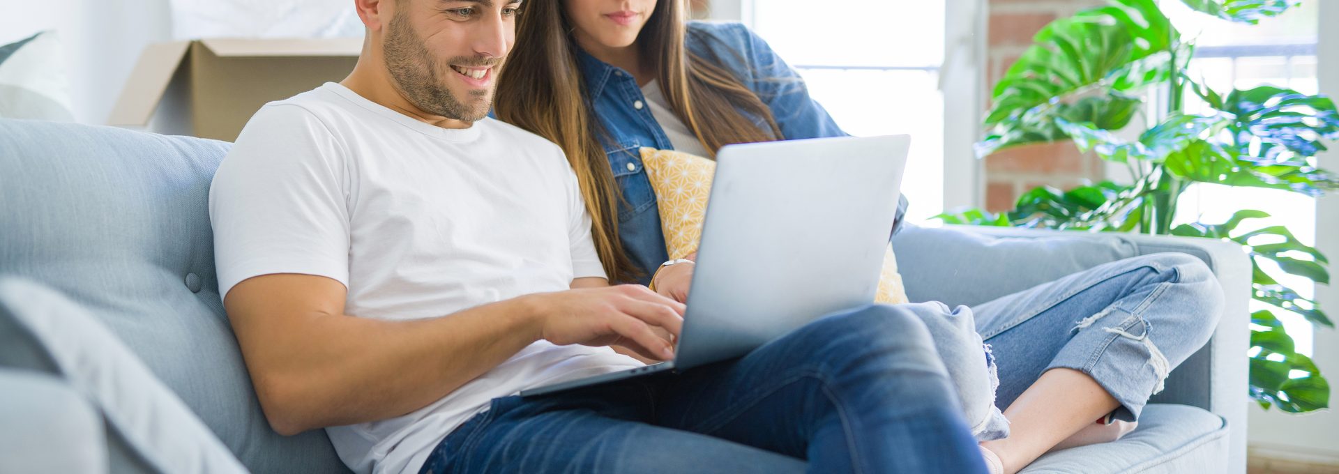 a man and woman sitting on a couch with a laptop at The Woodview