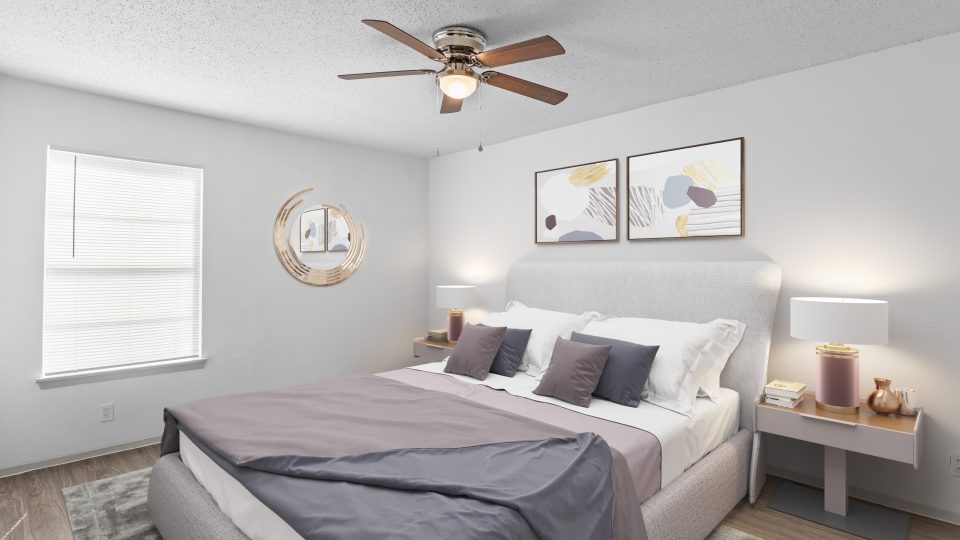 a bedroom with a ceiling fan and white walls at The Calypso Apartments