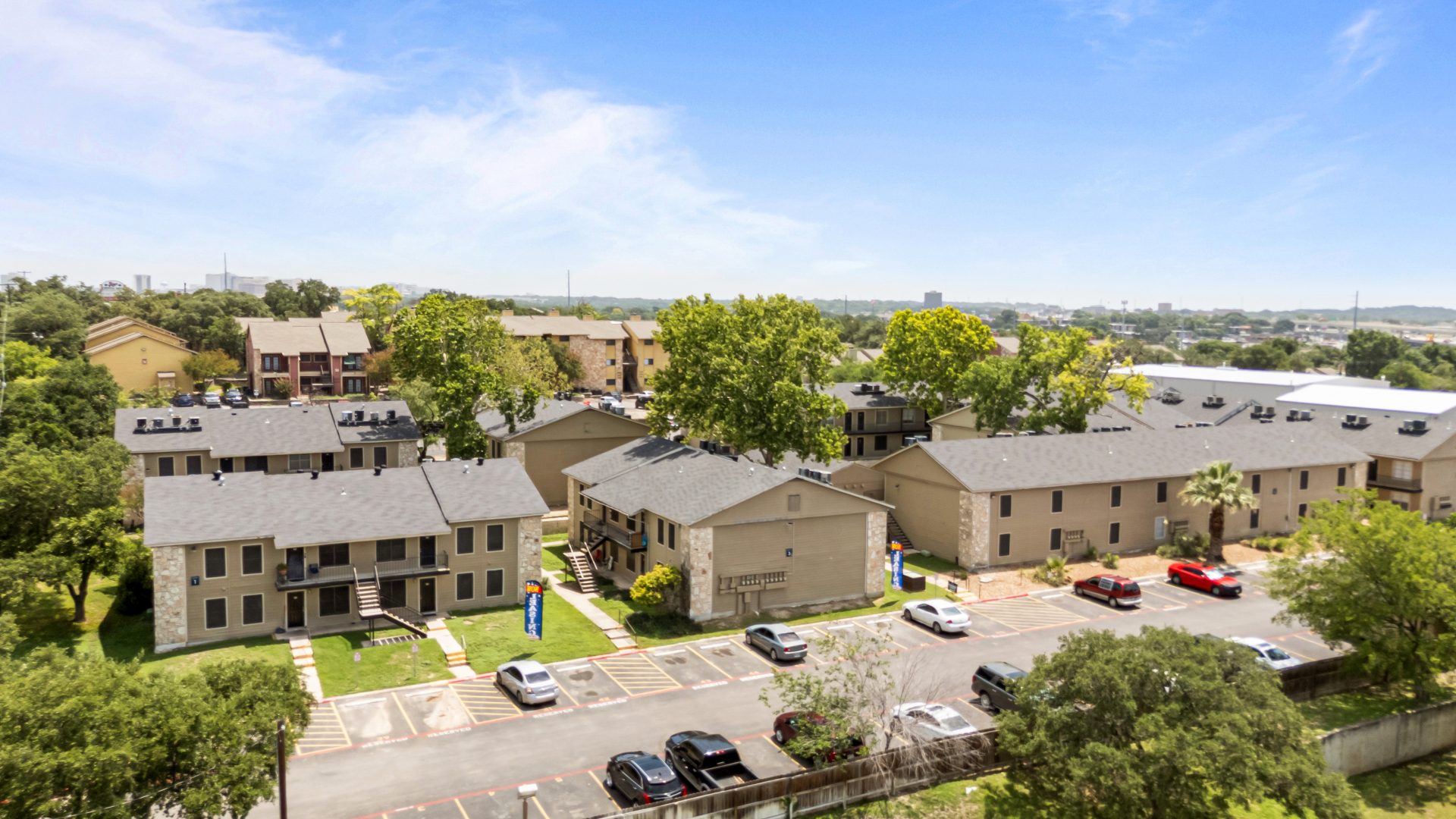 an aerial view of the apartment complex with cars parked in front at The Calypso Apartments